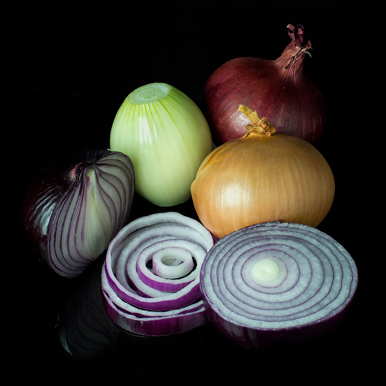Onions with green tops growing in soil.